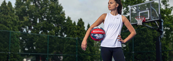 athlete posing with basketball in front of basketball hoop